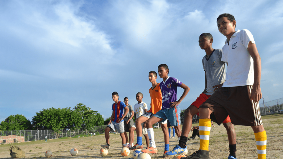 boys lined up with soccer balls on a field
